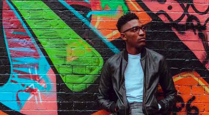 Category banner for winter jackets at Urbness Streetwear Store featuring a model in a stylish bomber jacket against a graffiti wall background, starting from $60.