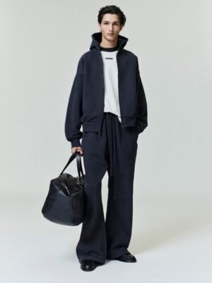 Full lifestyle views of a model wearing the authentic grey Essentials zip-up hoodie featuring a soft-touch logo finish, managed by Zizzle LLC.